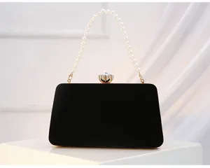 Detail view of black velvet evening clutch bag featuring elegant pearl handle and crystal clasp.