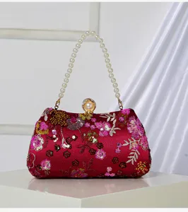 Detail shot of the red evening clutch featuring sequin floral embroidery and a pearl handle.