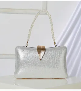 Detail view of silver evening clutch bag, featuring pearl handle and gold leaf clasp design.