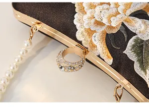 Elegant black satin evening clutch detail with exquisite gold embroidery and pearl strap.