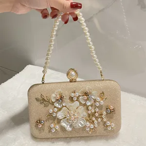 Close-up detail of golden glitter evening clutch bag with pearl handle and floral pearls.