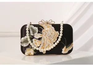 Elegant black satin evening clutch with pearl handle, golden bow clasp and floral embroidery.