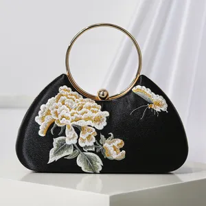 Bolso de noche de terciopelo negro con asa redonda dorada y elegante bordado floral.