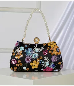 Close-up of exquisite floral sequin embroidery and pearl handle on black evening clutch bag.
