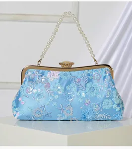 Close-up detail of the exquisite floral sequin embroidery and elegant pearl handle on evening bag.