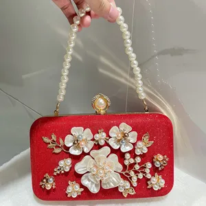 Elegant red sequin clutch bag with pearl handle and stunning floral rhinestone decor.