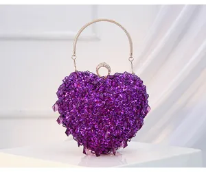 Detailed view of purple heart-shaped beaded evening clutch bag with metal ring handle and crystal clasp.