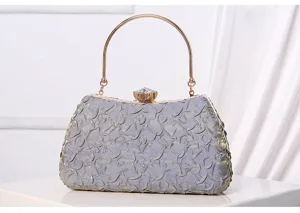 Elegant textured evening clutch detail showing metallic ring handle and sparkling crystal clasp.