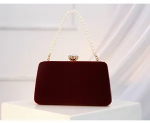 Burgundy velvet evening clutch bag detail, elegant pearl handle and sparkling crystal clasp.
