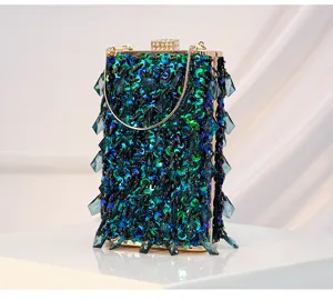 Close-up detail of green beaded evening clutch bag, sparkling sequins and hanging crystal drops.