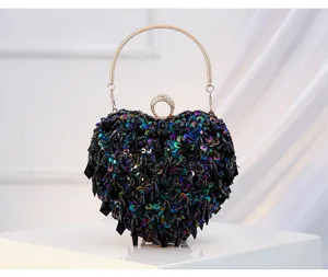Close-up detail of the black sequined heart-shaped evening clutch bag with beaded handle.