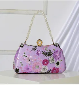 Detailed shot of a purple sequin embroidered evening clutch with a pearl handle and clasp.