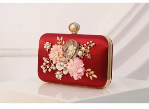 Detalle de bolso de noche rojo de satén, con diseño floral y perlas hechas a mano.