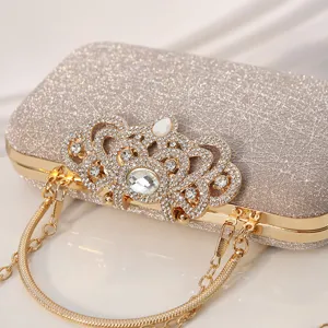 Elegante bolso de noche tipo clutch con corona de pedrería brillante y cadena dorada.