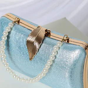 Elegant light blue glitter evening clutch bag featuring a stunning gold leaf clasp and chic pearl strap.