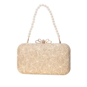 Elegant gold evening clutch bag with pearl handle and rhinestone bow clasp for women parties.