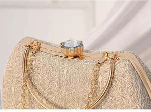 Gold lace evening clutch bag detail showing delicate floral lace texture, metal frame and crystal clasp.