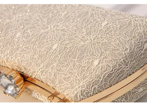 Close-up detail of luxury glitter lace evening clutch bag with gold metal frame and gem clasp.