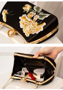 Detailed view of black satin evening clutch bag with gold embroidery, floral patterns and pearl clasp.