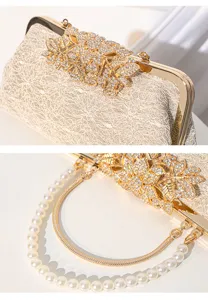 Elegant evening clutch bag detail showing rhinestone floral clasp, lace fabric and pearl strap.