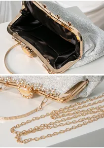 Detailed view of the elegant silver evening clutch bag with sparkling rhinestones and gold chain.