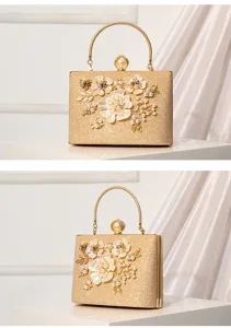 Elegant gold glitter evening bag detail with pearl floral appliques and metal handle.