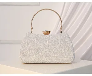 Detailed view of white lace evening clutch with elegant gold round handle and crystal clasp.