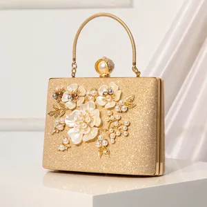 Elegant gold evening clutch bag with pearl floral decor, chic metallic handle for banquets.