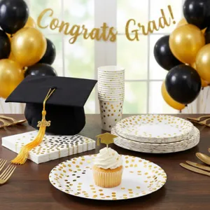 Detail view of black and gold polka dot graduation party paper tableware set with cap prop.