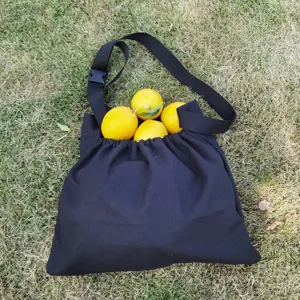 Detailed view of black outdoor foraging bag filled with fresh lemons on natural green grass.