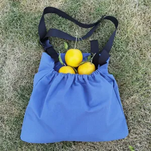 Outdoor fabric foraging bag detail showing blue pouch, black straps and fresh citrus fruits.