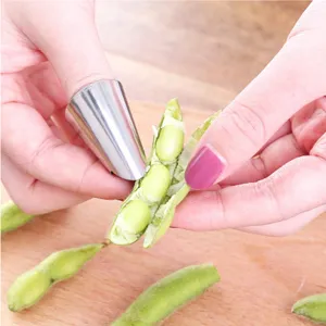 Detalle en primer plano del protector de dedo de acero inoxidable utilizado para pelar edamame.
