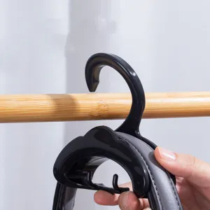 Detail shot of a black arched handbag hook hanging on a wooden rod for wardrobe storage.