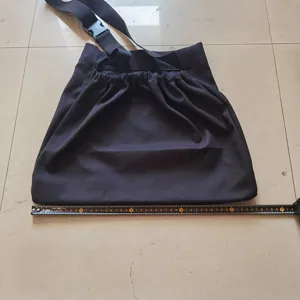 Detail view of black canvas foraging bag showing size with tape measure for outdoor harvest.