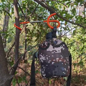 Outdoor Camping S-Haken und Tarn-Wasserflasche hängen in Waldszene für Ausrüstungs-Detailansicht