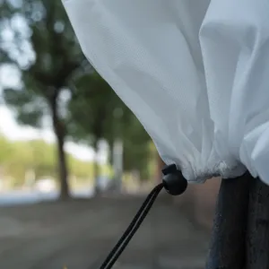 Close-up of white non-woven plant frost cover with adjustable black drawstring and toggle.