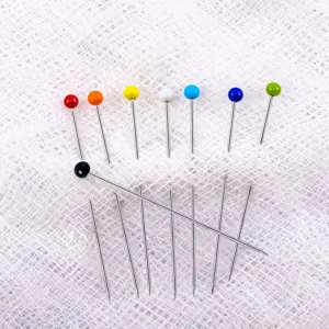 Gros plan d'épingles à tête de verre colorée, épingles de couture et de modélisme multicolores.
