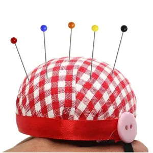 Coussin à épingles à carreaux rouges et blancs avec épingles à têtes colorées pour la couture.