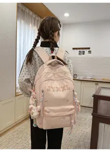 Detailed view of pink school backpack with cute bow embroidery and bear pendant in cozy room.