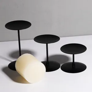 Matte black iron candle holders set with pillar candle, modern minimalist home decor detail.
