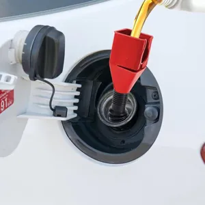 Detail shot of adjustable red and black plastic car fuel funnel inserted in gas tank inlet.