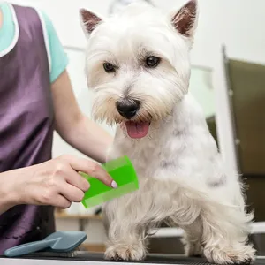 Detailed view of a green fine-toothed pet flea comb being used to groom a white dog.