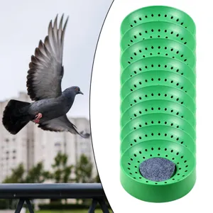 Close-up detail of green plastic pigeon nesting bowls stacked together with a soft grey pad.