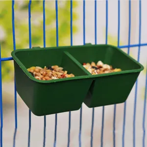 Close up view of the green double plastic bird feeder hanging on wire cage with seeds inside.