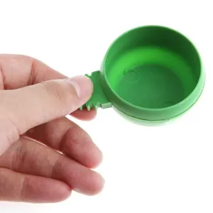 Close-up detail shot of a green plastic round bird food bowl designed for wire cages.