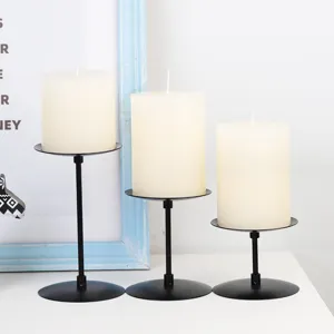 Set of three matte black iron pillar candle holders with white candles for home decor and dining.