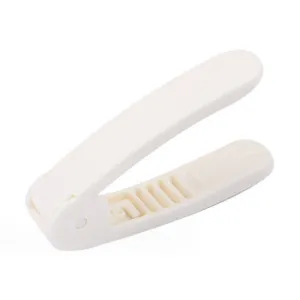 White plastic peanut sheller detail close-up, manual nut cracker tool with inner slot structure.