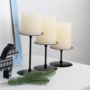 Close-up detail of black iron pillar candle holders with white candles for home decor.