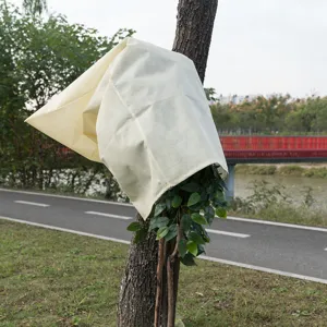 Detailed view of the beige non-woven winter plant frost protection cover in outdoor garden use.