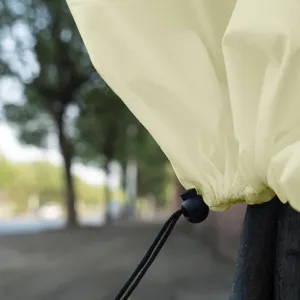 Plant frost protection cover detail with beige non-woven fabric and black cord lock.